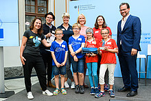 Bronze: Grundschule Adelby (Schleswig-Holstein) Tanja Loitz (co2online, li.), Inken Erichsen (Schulleitung), Vanessa Wawerek (Lehrerin) und SchülerInnen der Grundschule Adelby, Sabine Recupero als Vertreterin des Paten EKSH Gesellschaft für Energie und Klimaschutz Schleswig-Holstein GmbH, Parlamentarischer Staatssekretär Florian Pronold (re.), Moderator Ben (2. v. li.).