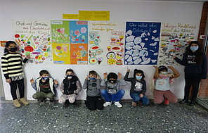 Die Energiemanager*innen stehen vor ihren selbstgestalteten Plakatwänden, die ihre Klimaschutz-Projekte thematisieren.