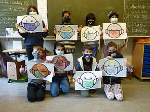 8 Grundschüler*innen halten selbstgemalte A4-Blätter hoch.