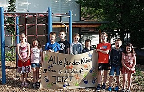 Die Motivierer*innen aus Rheinland-Pfalz Die Schüler*innen der Grundschule am Jakobsweg stehen mit selbst gestaltetem Klimaschutz-Plakat vor dem Klettergerüst